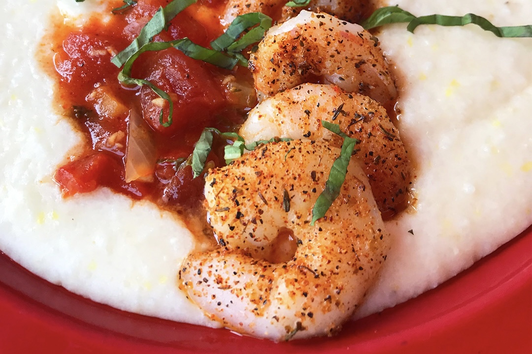 Shrimp and grits served on a red plate
